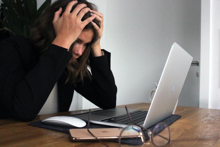 Женщина сидит в стрессе перед ноутбуком